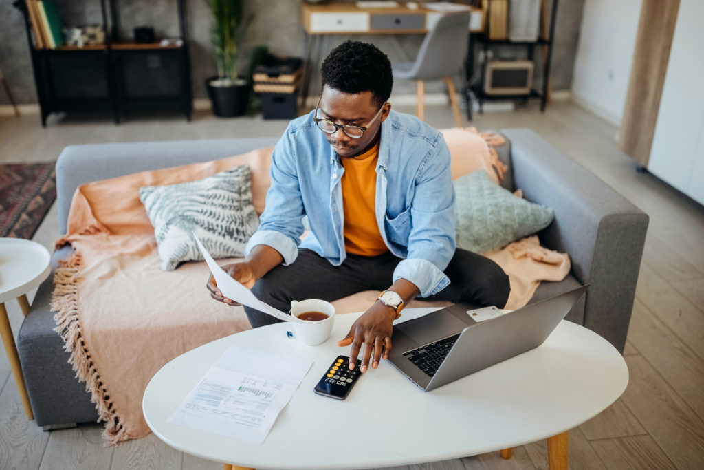 young working american holding paycheck and student loan bill side by side