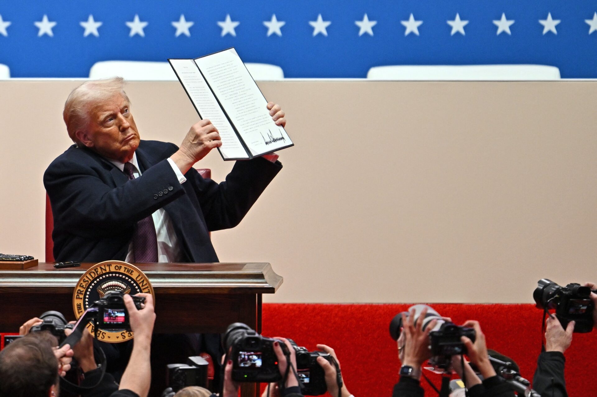 President Trump signing executive orders with American flags in background