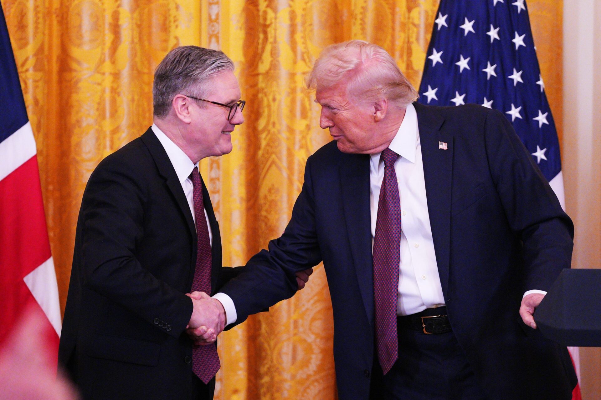 President Trump and PM Starmer shaking hands with American and British flags behind them