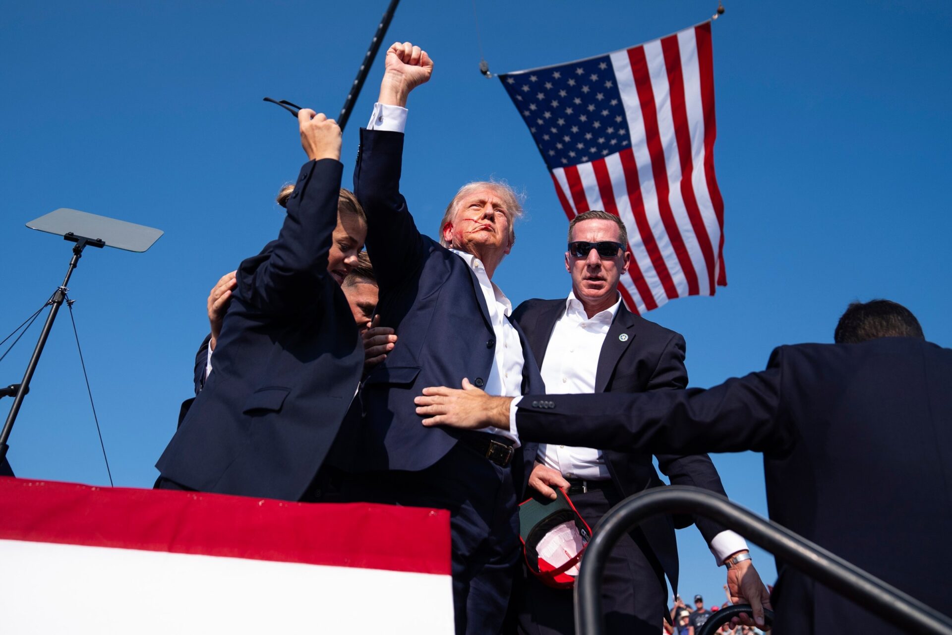 donald trump walking confidently at rally with american flag in background