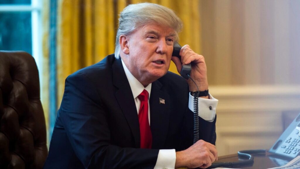 president donald turmp on the phone behind the presidential desk in the white house oval office
