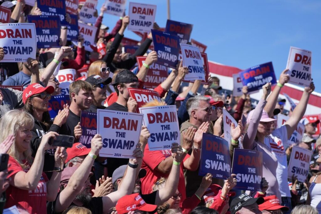trump rally visitors holding up 'drain the swamp' signs