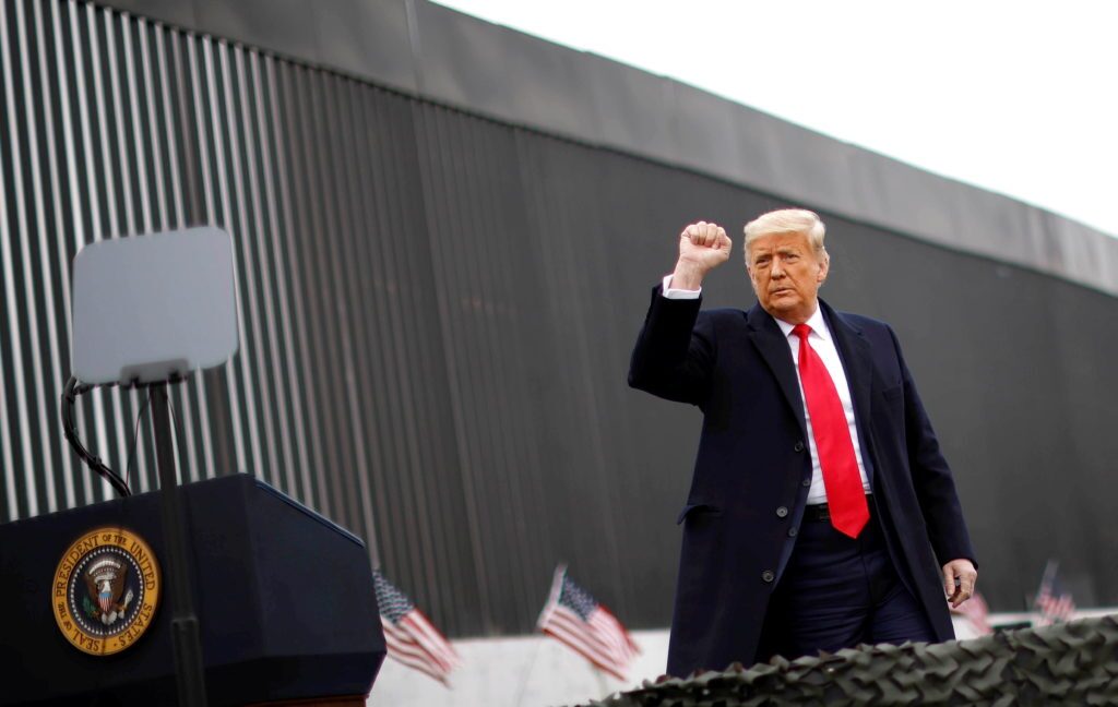 trump raising fist in front of border wall