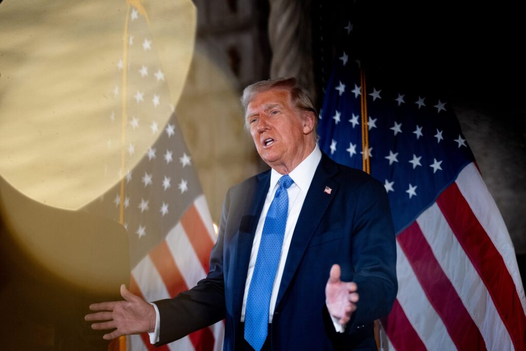 president trump holding a speech with american flags behind him