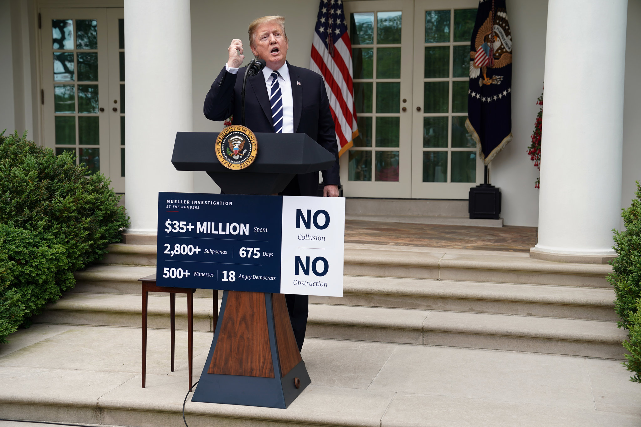 Trump speaking with a "No Collusion, No Obstruction" banner in the background