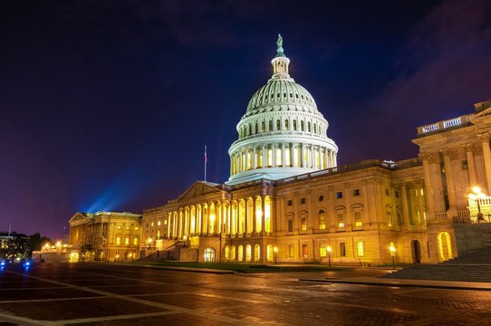 U.S. Capitol building at night with a spotlight on the dome