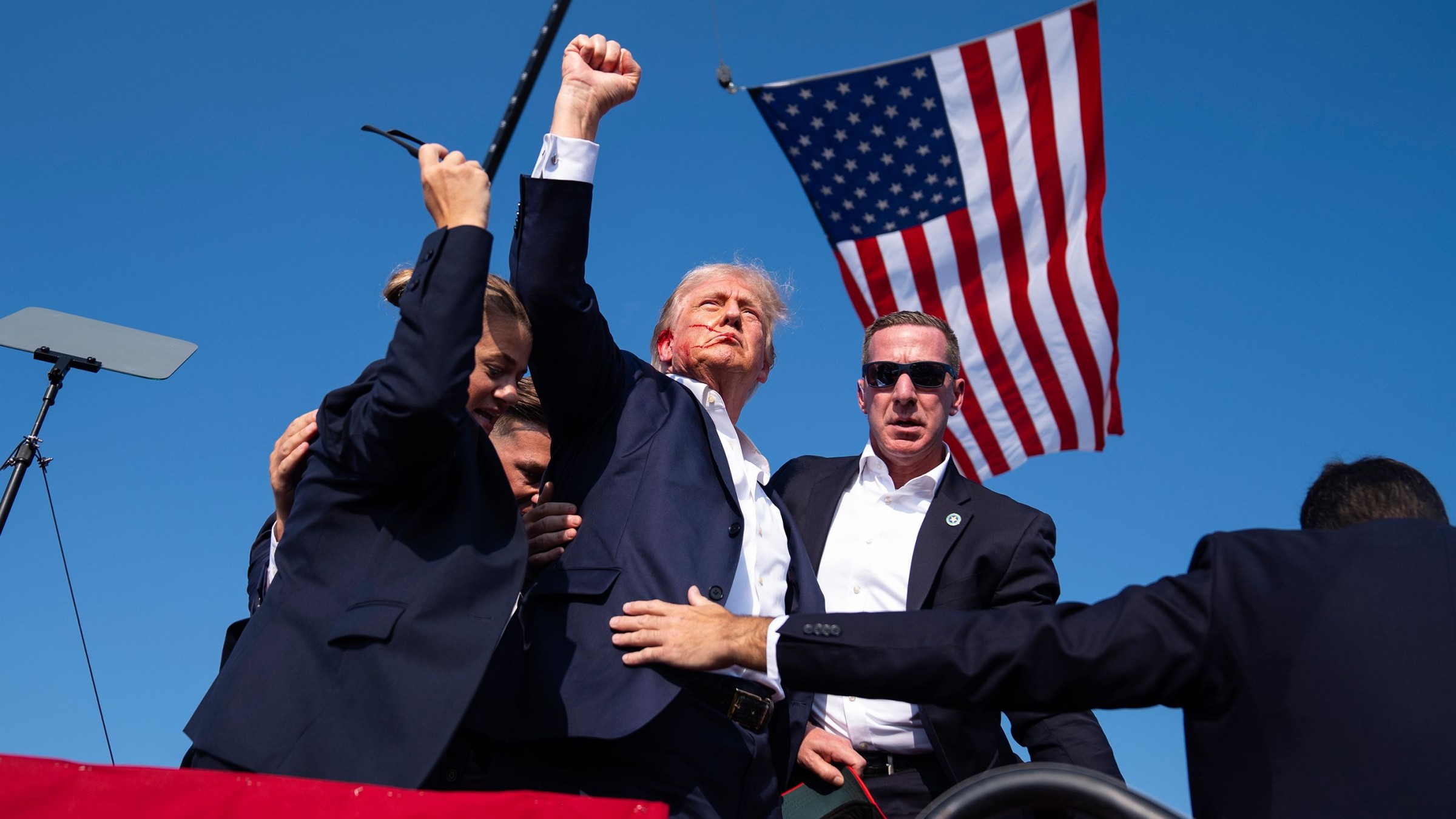 Trump speaking at a rally with American flags in background