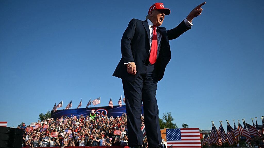 trump saluting on stage with american flags