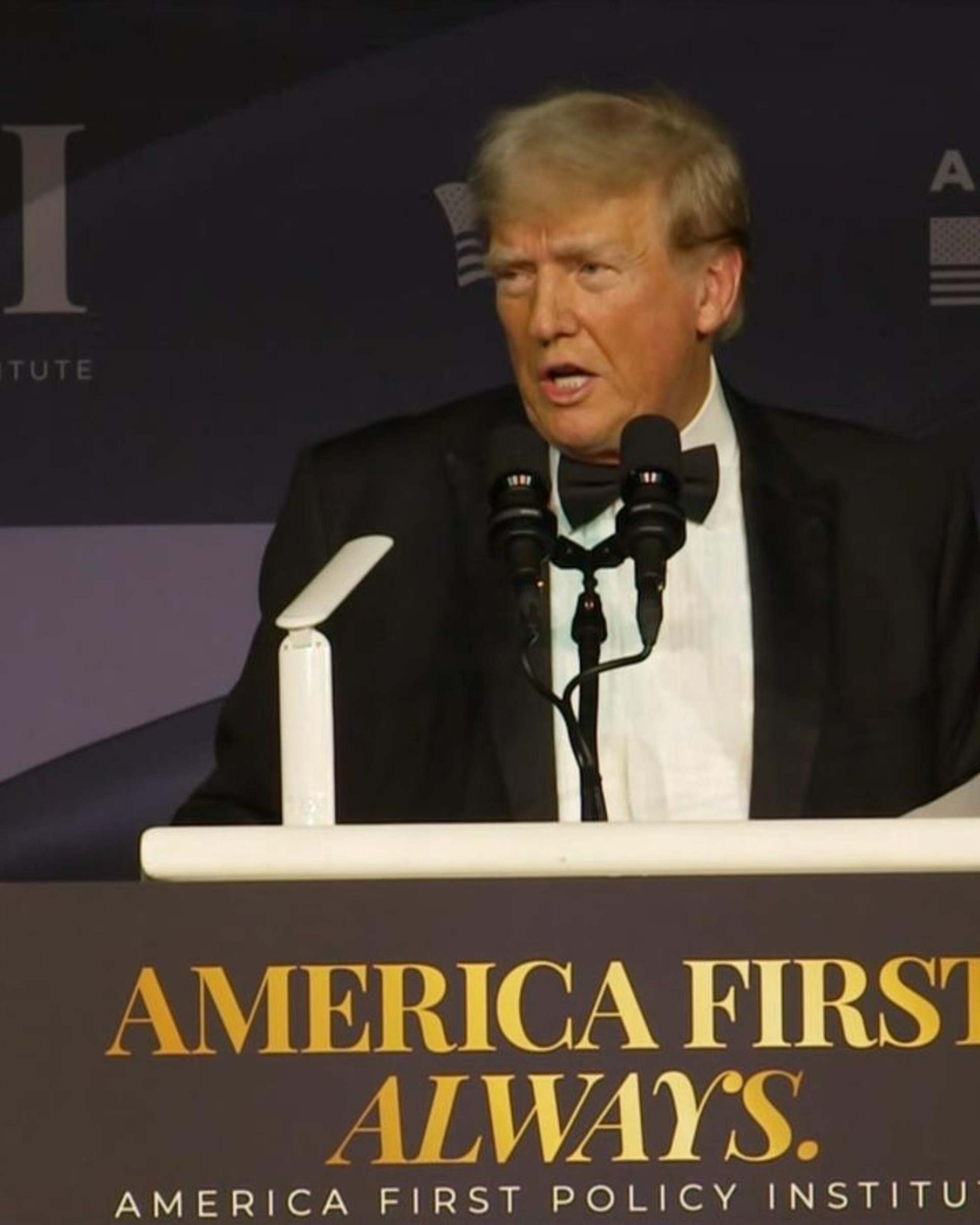 donald trump speaking in front of 'america first' signs