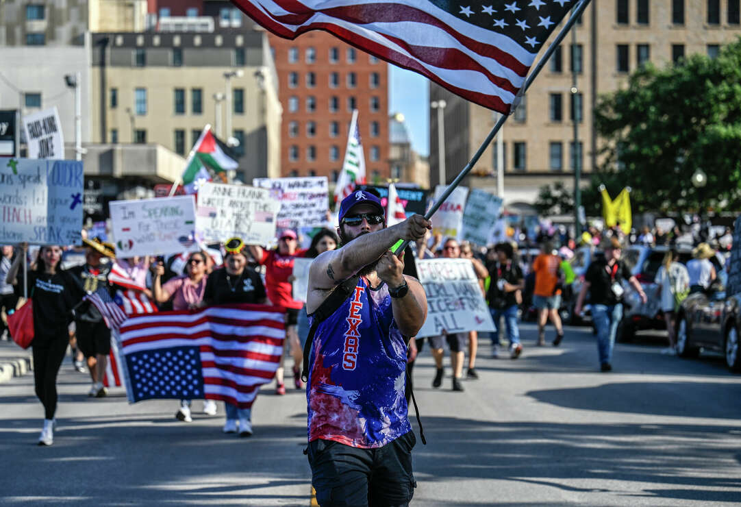 A crowd of people, some holding American flags, at a rally