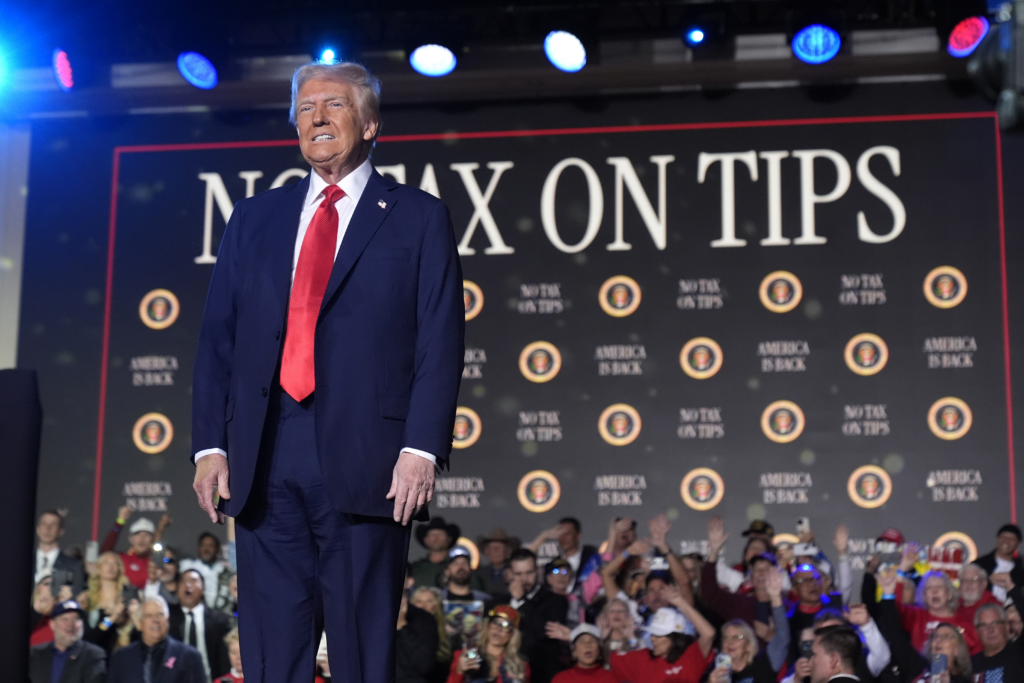 donald turmp on stage with 'no tax for tips' background