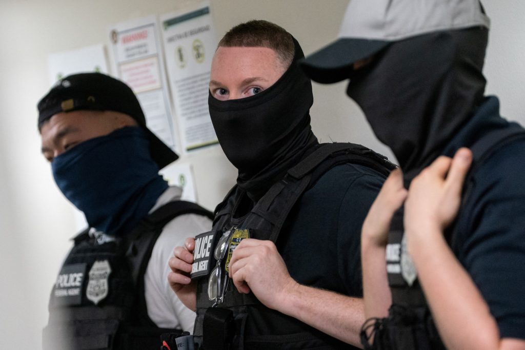 A team of U.S. Immigration and Customs Enforcement (ICE) officers wearing masks