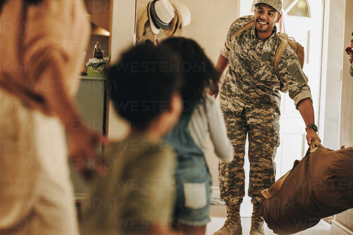 american soldier in uniform reuiniting with his wife and children