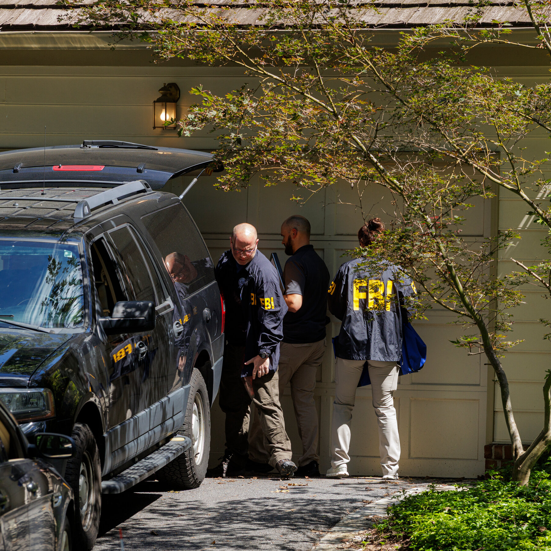 FBI agents carrying boxes labeled "EVIDENCE" out of a residential home, symbolizing a raid. August 2025.