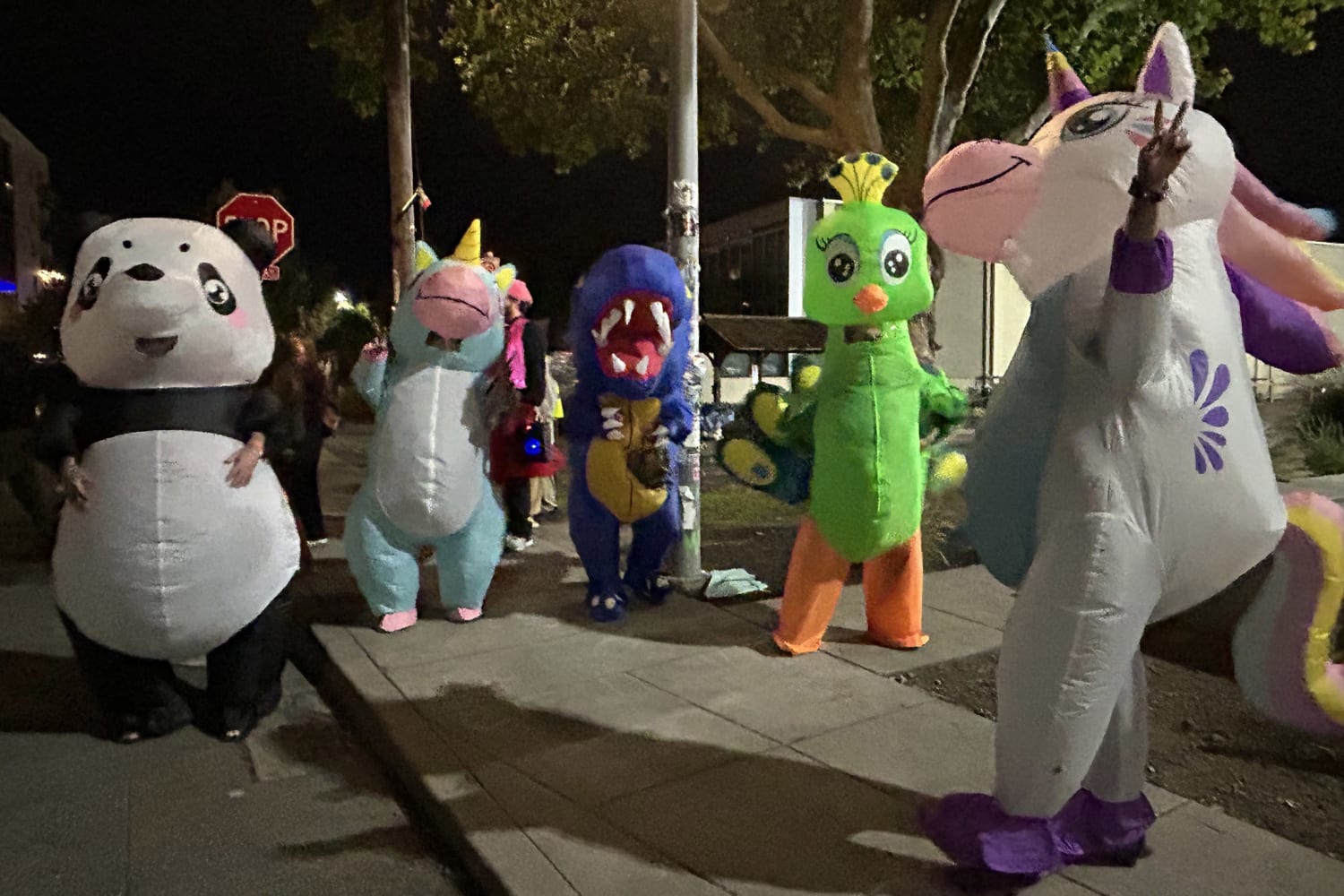 Protesters in inflatable dinosaur and unicorn costumes outside a building in Portland, October 2025.
