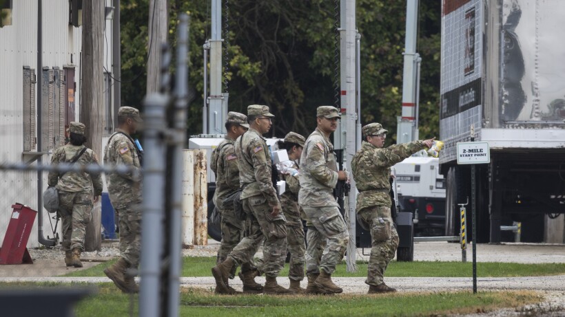 Texas National Guard troops in uniform standing guard near an ICE facility in Chicago, October 2025.